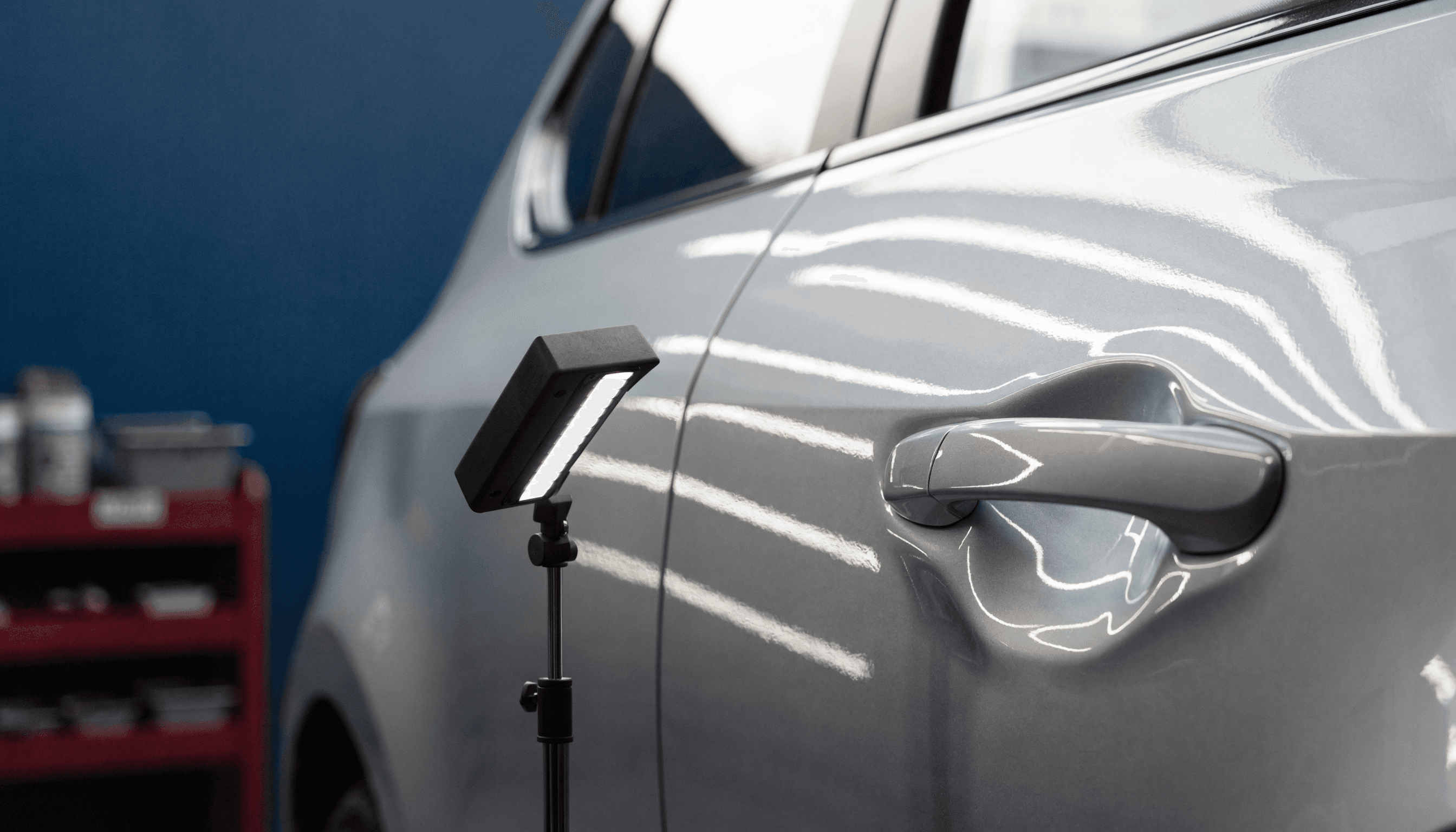 Inspection light revealing reflections across a silver car door