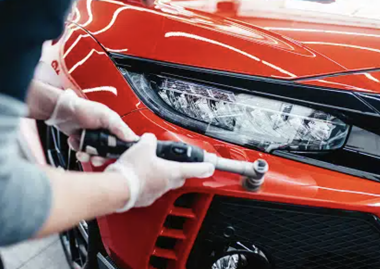 Bumper of red car being waxed after dent repair